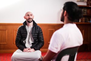 Two men having a discussion in a room, focusing on fatigue management plans for NDIS participants, with one man attentively listening to the other.