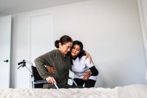 Caregiver assisting an elderly woman in a wheelchair with personal care tasks at home