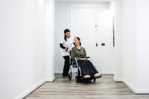 A support coordinator assists a smiling woman in a wheelchair, illustrating NDIS choice and control.