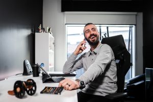 A man talking on his phone while working with various gadgets, highlighting the technology for disabled people for productivity.