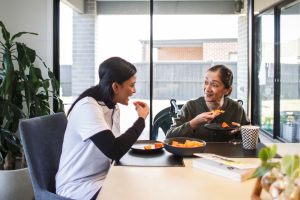 A support coordinator and an elderly woman enjoying a meal together, showing NDIS choice and control in daily living activities.