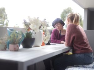 Two women having a discussion on a balcony, illustrating outdoor social activities for disabled persons, promoting connection.