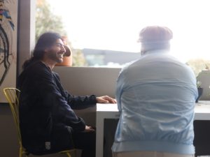 Two people smiling while having a conversation, representing NDIS assistance with household tasks and support for daily needs.