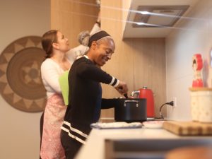 Two women cooking together, representing inclusive kitchen activities for disabled persons, fostering collaboration and independence.