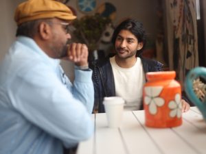 two man talking while drinking while sitting on a table