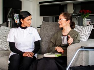 a women with NDIS provider talking while sitting on a sofa