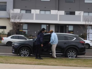 Two people near a parked SUV discussing accessible transport options for disabled individuals.