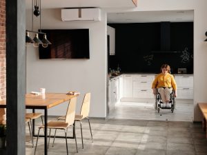 Woman in a wheelchair navigating a spacious house, promoting disability and independent living in a comfortable environment.