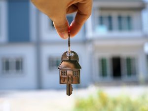 Hand holding keys with a house-shaped charm, symbolising homeownership and independence for people with disabilities.