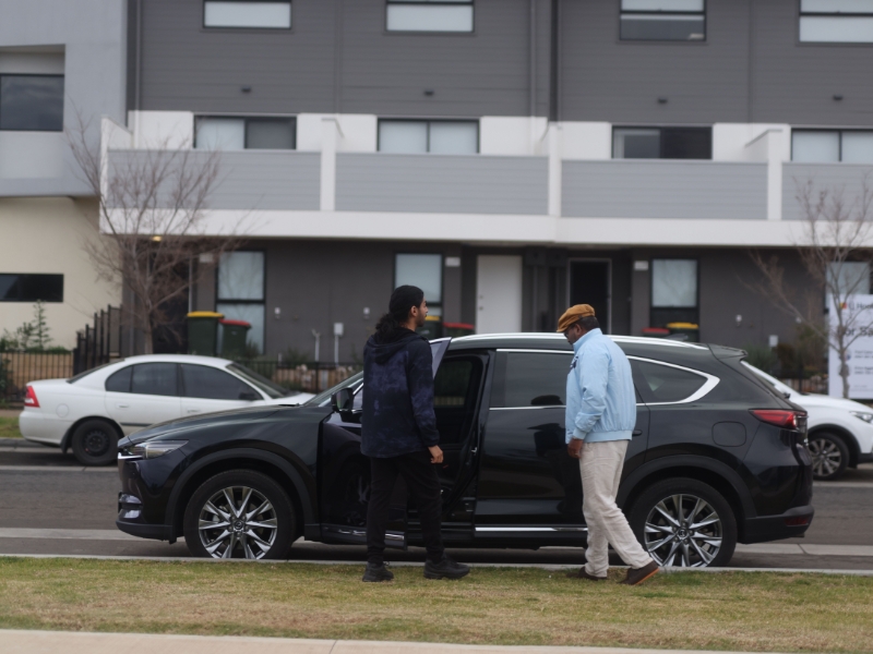 Support for transport accessibility, with a person assisting a man into a vehicle for easier access.