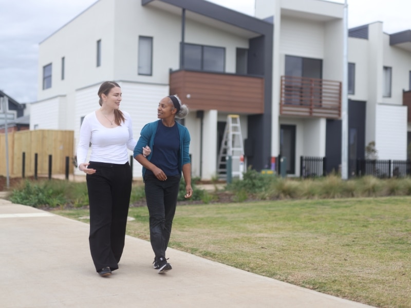 Two women walking outdoors, smiling and chatting during ndis community events.