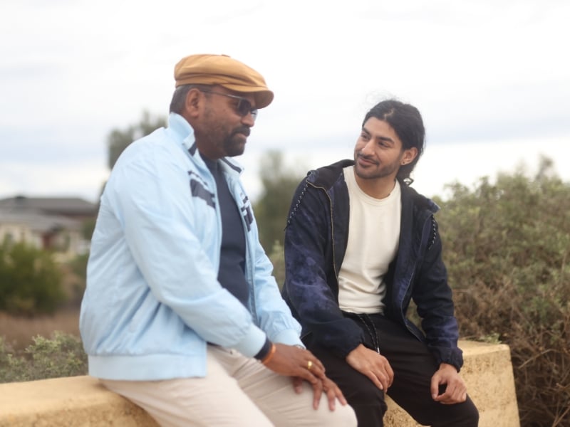 Two men having a relaxed outdoor conversation, reflecting on goals and progress during a daily living skills assessment session.