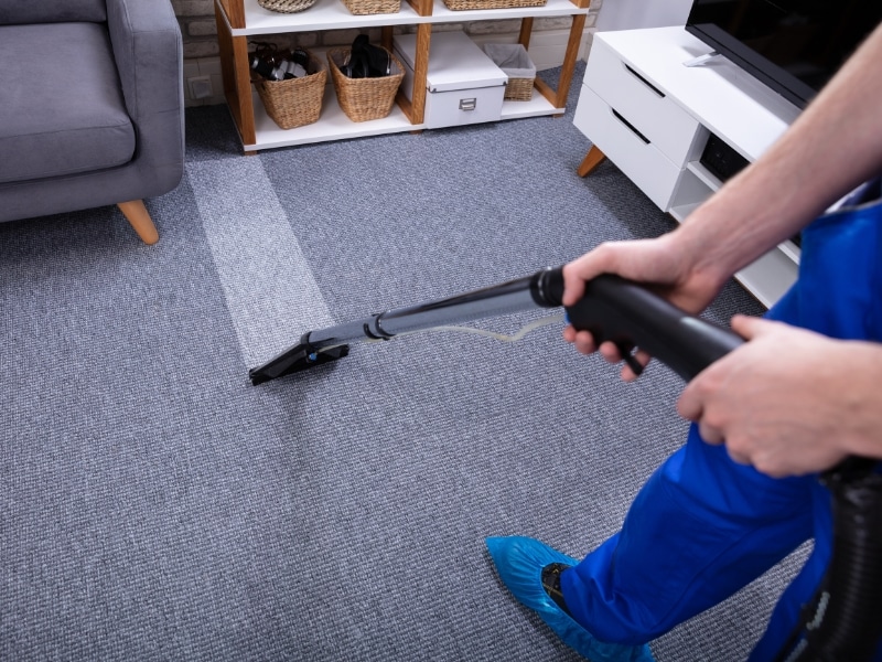 NDIS carpet cleaning professional steam-cleans carpet in a living room with visible results.