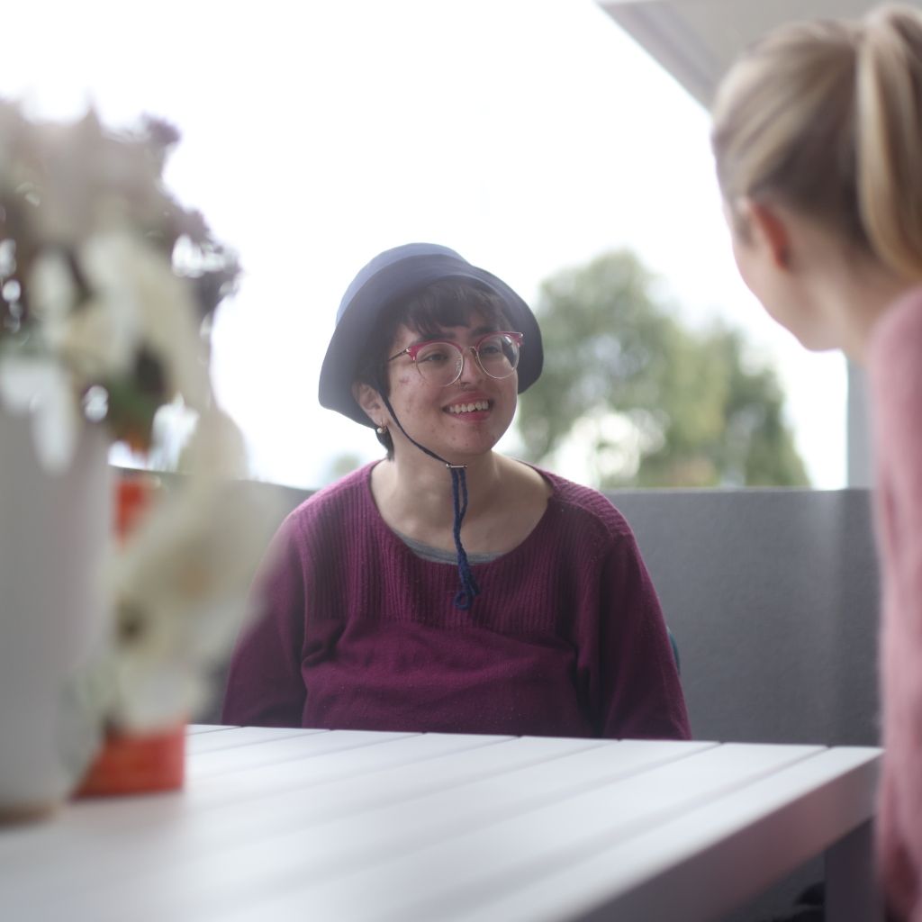 NDIS participant smiling while speaking with a support worker about accommodation goals