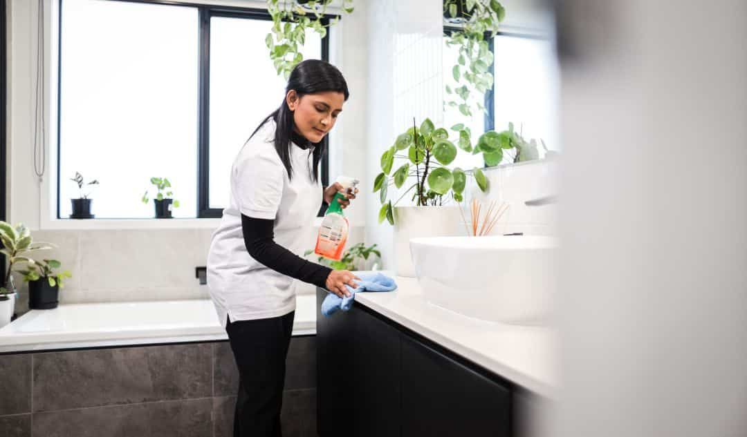 Support worker cleaning a bathroom vanity as part of NDIS household tasks