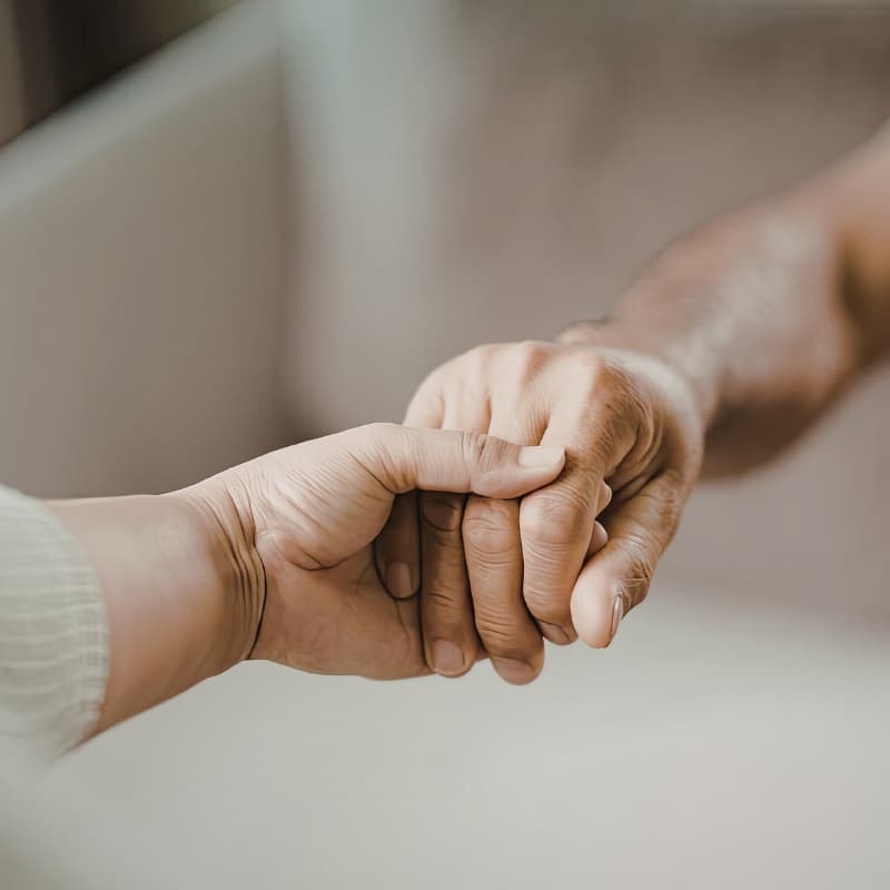 ndis support worker gently holding a participant’s hand in a close-up, conveying care, trust and reassurance.
