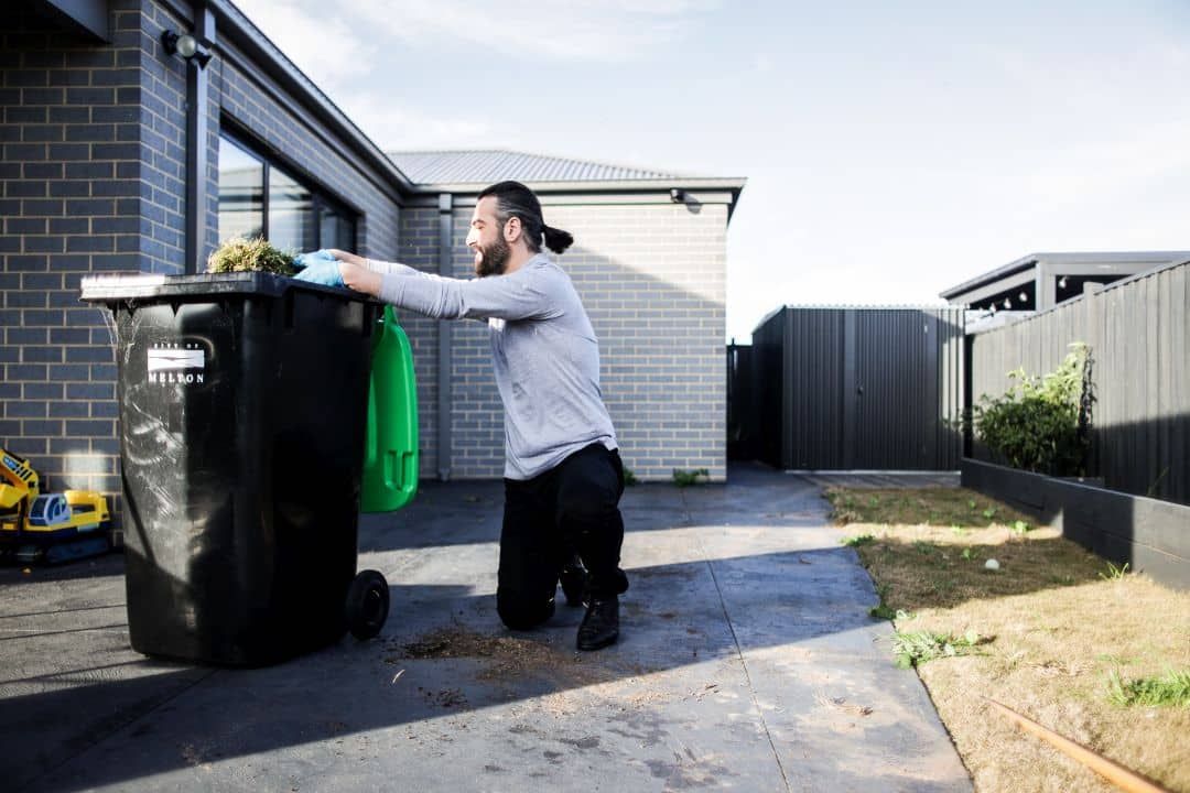 Man moving a wheelie bin outside a home during household tasks support