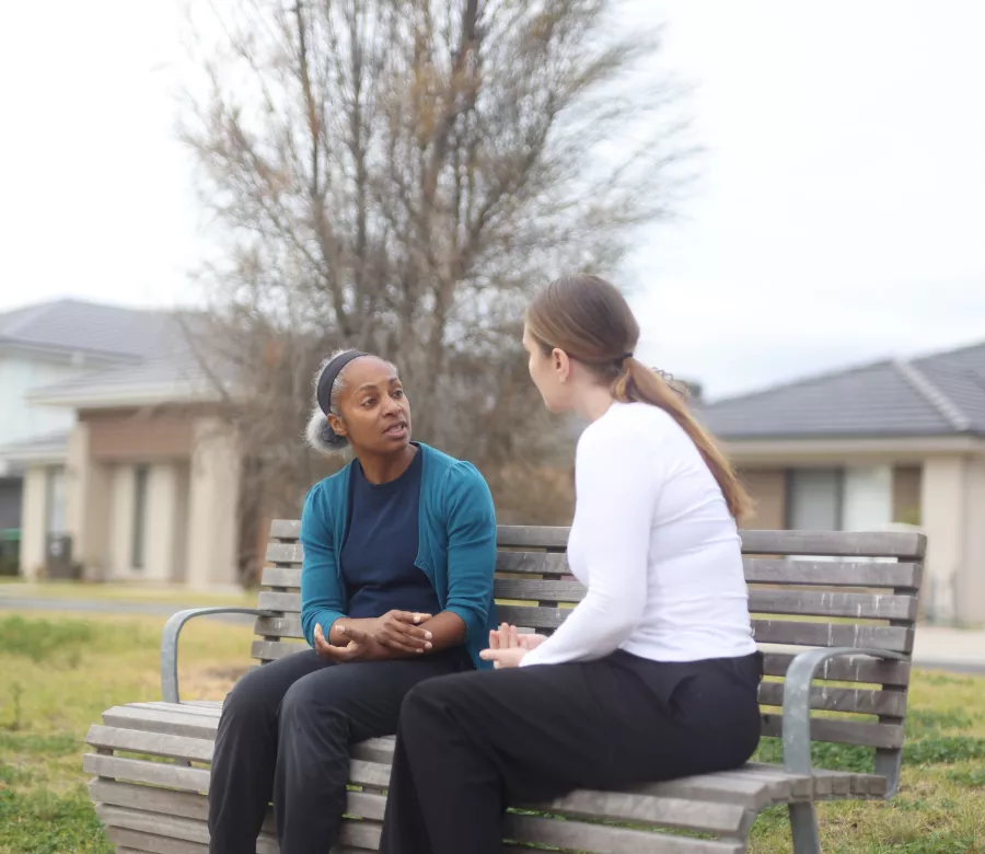 A support worker and participant talking warmly at the front door of a home in Stonnington.